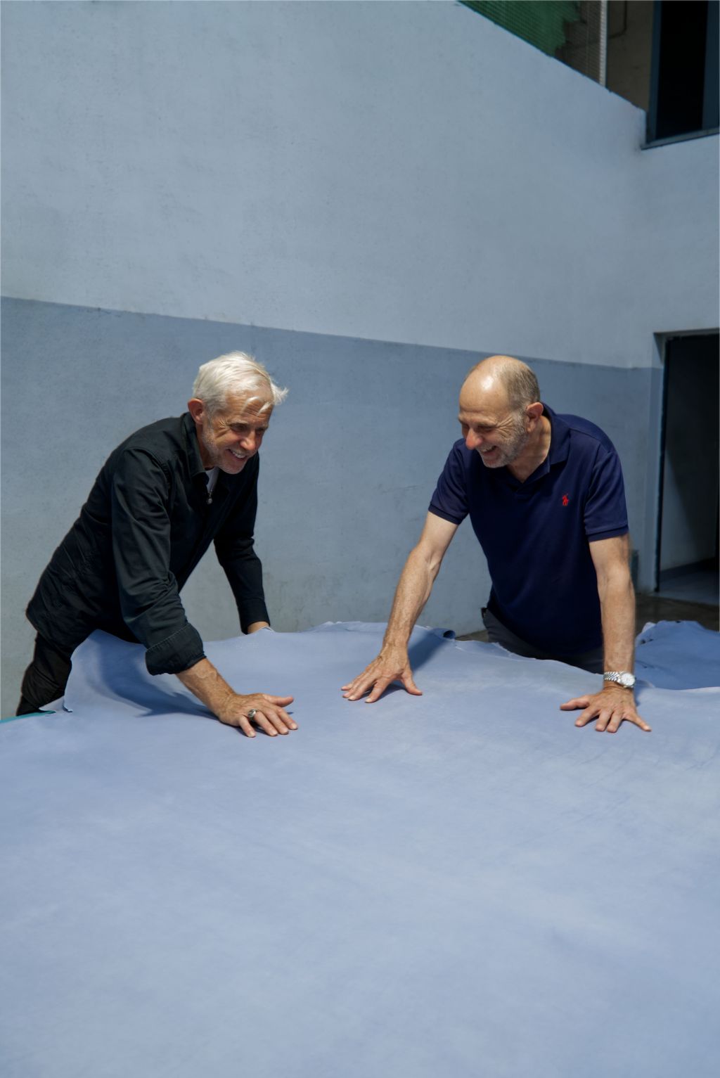 Two men with hands on a large blue leather hide in the factory courtyard Two men with hands on a large blue leather hide in the factory courtyard